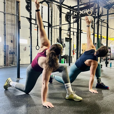 Two woman stretching their arms.