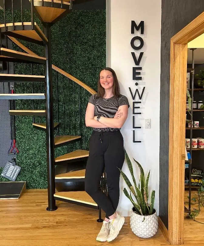 Chiropractor Hannah Spaulding smiling next to a Move Well sign.
