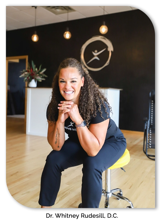 Chiropractor Whitney Rudesill sitting on a chair smiling.