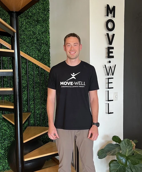 Chiropractor Austin Werdin standing next to a Move Well sign.